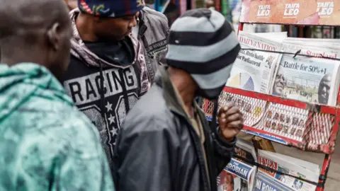AFP Residents look at newspapers displayed at a stand in Mathare, Nairobi following Kenya's general election on 12 August 2022