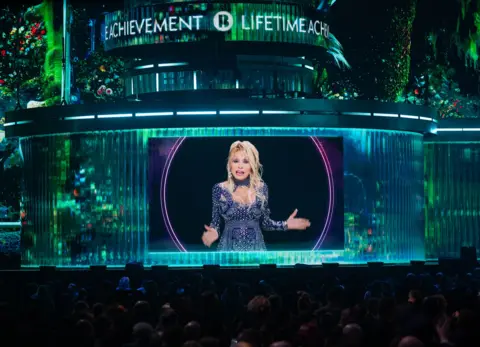 Samir Hussein/WireImage via Getty Images Dolly Parton gives a speech after Ozzy Osbourne won the Lifetime Achievement Award during The BRIT Awards 2026 at Co-op Live on February 28, 2026 in Manchester, England. 