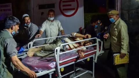 Getty Images Hospital staff bring an injured man for treatment after the Kabul airport attack