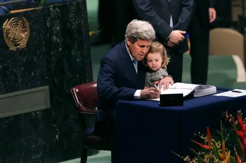 Getty Images John Kerry is joined by his granddaughter as he signs the Paris climate agreement in 2016