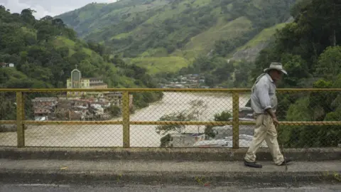 Pablo Cuellar A man walks over a bridge over the river Cauca