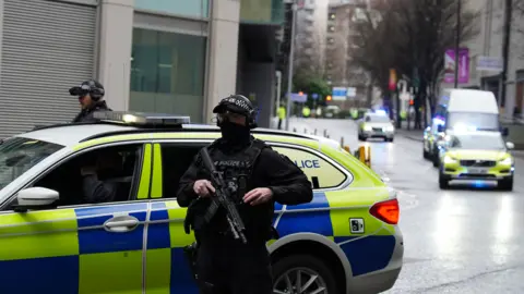 PA Media Armed police escort a van into Manchester Crown Court