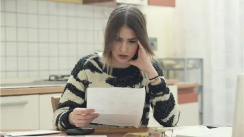 Getty Images Woman looking at bills