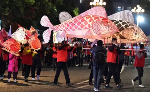 China News Service / Getty Folk artists and children parade with fish lanterns in Sanming, Fujian Province, China