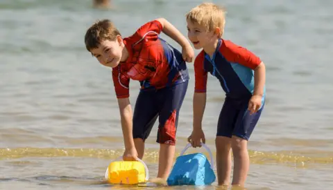 Getty Images Hamish and William fill their buckets with water at the beach on July 17, 2021 in Weymouth