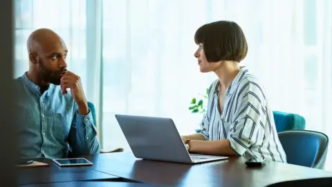Getty Images An employee talks to a female boss