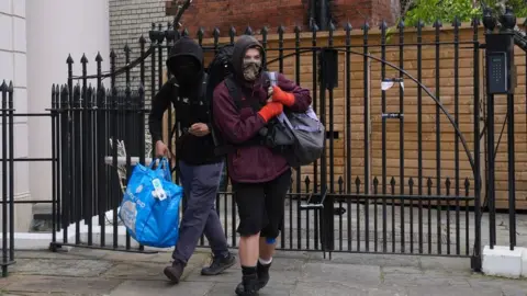 Lucy North/PA Two squatters leaving Gordon Ramsay's pub