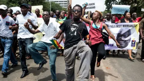 AFP Demonstrators sing, dance and shout political slogans during a march to mark the one year anniversary of the disappearance of Itai Dzamara on March 9, 2016 in Harare. Dzamara a former journalist before he turned political activist was the leader of a group called Occupy Africa Unity Square park which sought to pressure Mugabe to step down for presiding over the collapse of the economy.