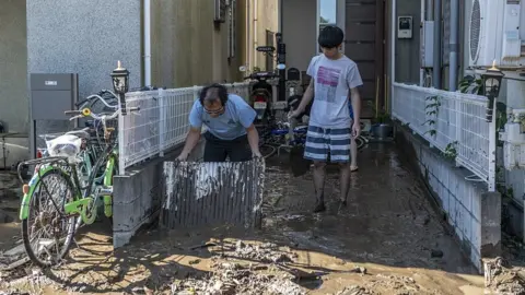 Getty Images People clear mud from their homes after being flooded during Typhoon Hagibis, on October 13, 2019 in Kawasaki, Japan