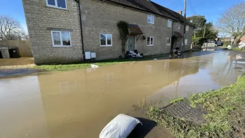 BBC Flood water in front of a double-fronted stone-built house