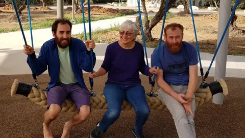 Family handout Peace activist Vivian Silver, centre, sits on a swing next to her two sons, including Yonatan Zeigan on the left