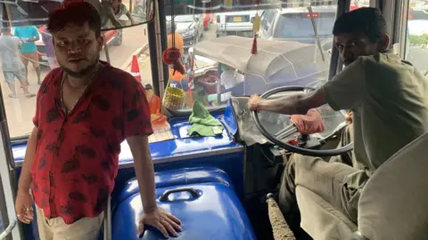 Guna, a bus conductor, and driver Nishantha are pictured inside a bus as they queue for petrol in Colombo