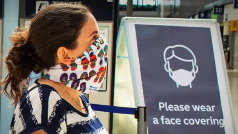 Alamy Woman at railway station wearing a face mask