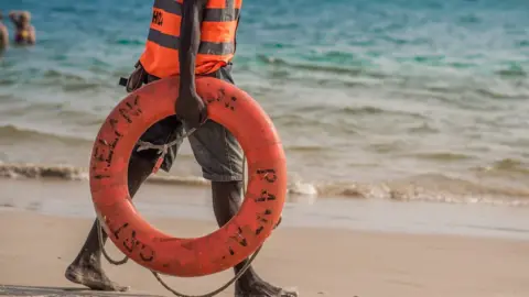 BBC A lifeguard holding a lifebuoy on the beach in Lagos, Nigeria