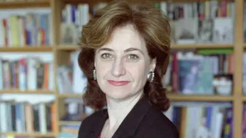 Ben Jones Image of Nicolette Jones looking at the camera sitting in front of a bookcase