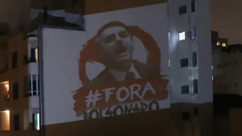 Reuters An image depicting Brazil's President Jair Bolsonaro and the phrase "Out Bolsonaro" projected onto a building in Sao Paulo (25 March 2020)