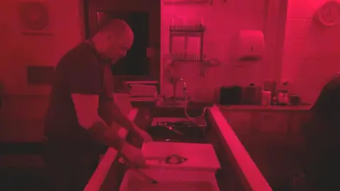 Man processing a photograph at a darkroom in Bristol