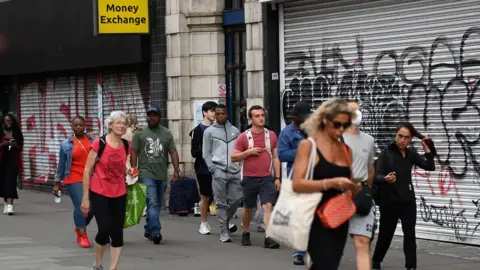 ANDY RAIN/EPA-EFE/REX/Shutterstock People walking past shops with shutters down in London