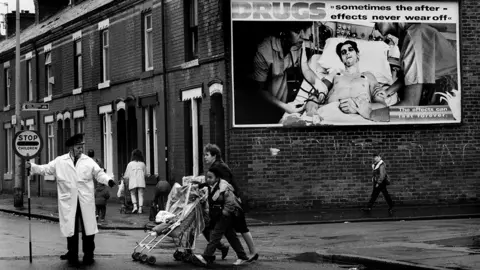 Getty Images A lollipop man guides children to school across a road in Moss Side