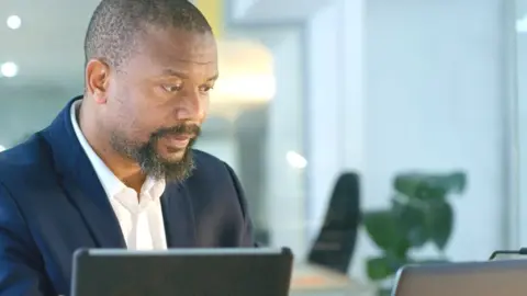 A man looking at a phone and tablet