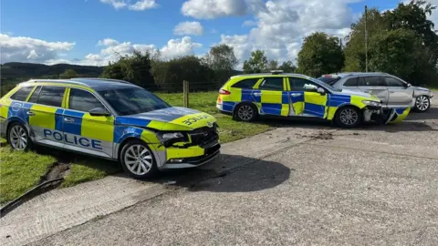 PSNI Three police cars showing damage after being rammed by tractor