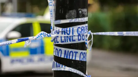 A close up of police tape wound around a telegraph pole