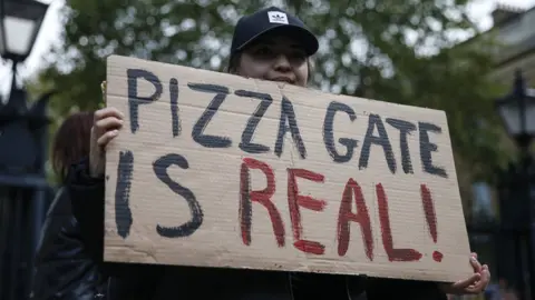 A protestor holds a sign during a "Save our Children" rally outside Downing Street on October 10, 2020 in London