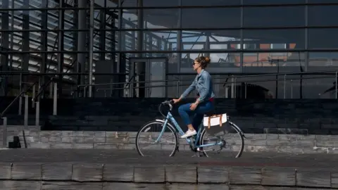 Sustrans Cymru Woman riding bike past the Senedd