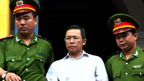 AFP Pham Minh Hoang (C) being led out from the courtroom at the Ho Chi Minh City People's Court House on 10 August 2011.