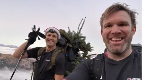 ED JACKSON Ed Jackson and Ross Stirling on part of their climb. They are both smiling. Ed is wearing a Santa hat.