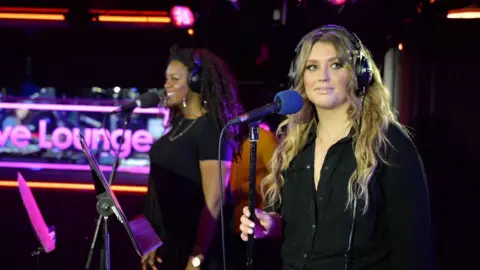 Ella Henderson wearing headphones and singing in the BBC Live Lounge