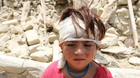 Getty Images Child outside destroyed home in Khost area