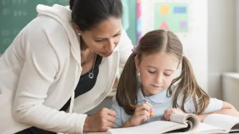 Getty Images Teacher helping pupil in classroom (stock photo)