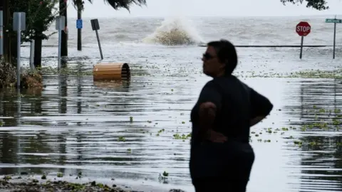 EPA A woman stands in front of a flooded road near Lake Pontchartrain as hurricane Barry approaches in Mandeville, Louisiana