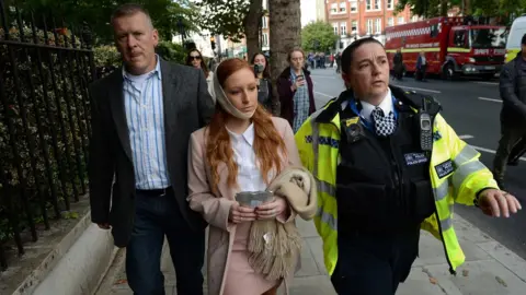 Chris J Ratcliffe A female casualty is led from the scene by a police officer