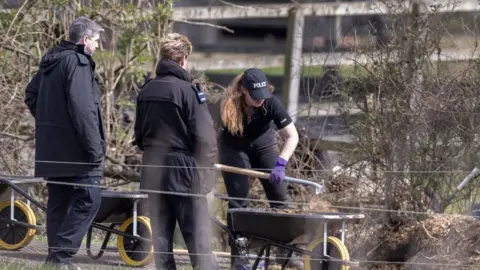 Peter MacDiarmid/Shutterstock police dig grounds at a farm