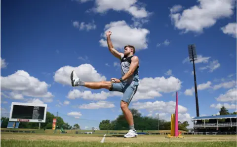 Getty Images David Willey in the middle of bowling. There are blue skies and clouds behind him.