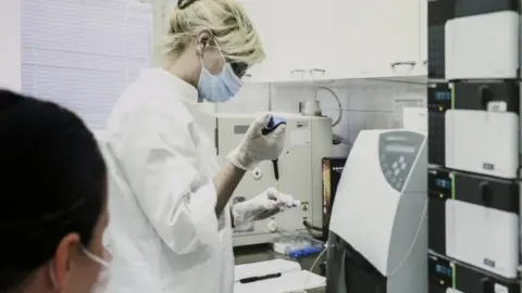 EPA A staff member at the Torlak Institute of Virology, Vaccines and Sera looks at a photo of a colleague in Belgrade, Serbia, 15 April 2021