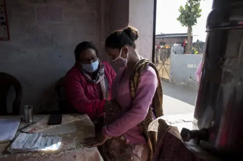 Mansi Thapliyal Kiran Mal, a female health worker, attending to a patient in Uttarakhand