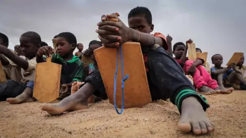 Children on the ground read from boards