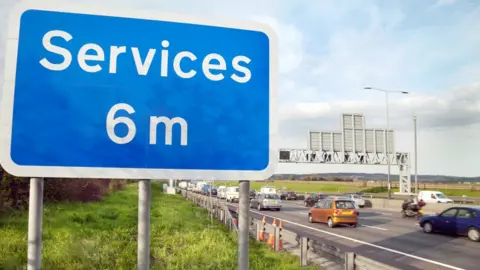 Alamy Motorway services sign next to a busy road