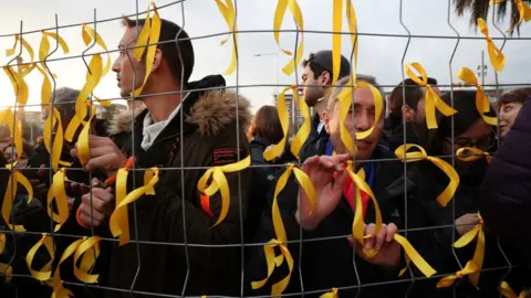 Reuters People tie yellow ribbons to a fence, as they protest in front of Germany's consulate after former president Carles Puigdemont
