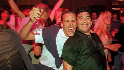 Getty Images A fan smiles and hugs Diego Maradona during a party at the Conrad Hotel in 1999 in Punta del Este, Uruguay