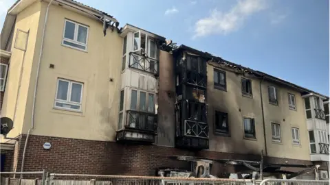 BBC A block of flats with the exterior blackened by fire and smoke