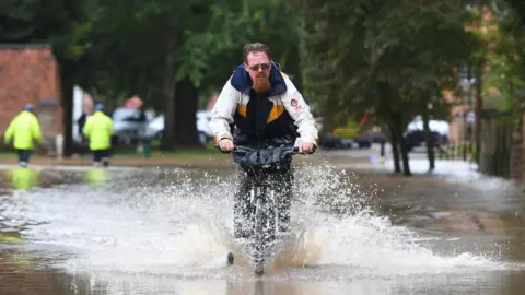 PA Media A cyclist riding through floods in Leicestershire