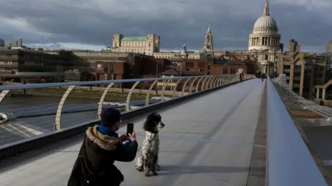 Getty Images Man takes a photo of his dog on a deserted Millennium bridge in London