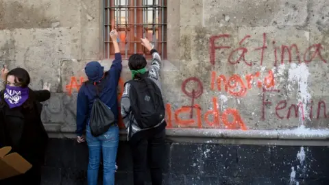 Getty Images Demonstrators paint windows as they gather outside the National Palace, in Mexico City, on February 18, 2020, to protest against gender violence.