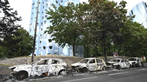 Getty Images Burnt cars line the street at the foot of the Pablo Picasso estate in Nanterre, west of Paris, following riots after a 17-year-old boy was shot in the chest by police at point-blank range in Nanterre, France