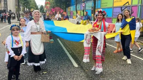 BBC A group holding a large Ukrainian flag in the Mela parade