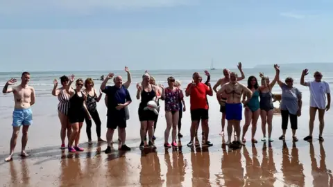 Nightstop Group photo on the sand in front of the sea